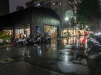 motorcycles parked next to each other on a rainy street corner in front of a building