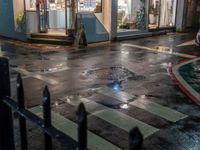 a street scene with a manhole and the pedestrian crossing crosswalk at night time