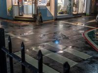 a street scene with a manhole and the pedestrian crossing crosswalk at night time