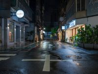 a wet street with a white sign and a building at night with many windows on the sides