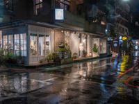 a wet sidewalk in the city at night near a cafe in the rain with lights shining