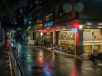 a city street has people at a cafe that is lit up with red and blue lights