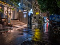 a rainy night with people walking on the sidewalk and parked vehicles on the street,