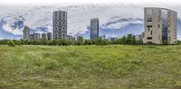 a view of some tall buildings from the side by side in a field of green grass