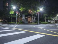 an empty crosswalk in a street at night with multiple lights on the street below it