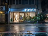 a store in the rain on the side of the street by the building with a blue sign saying, ohcher store