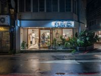 a store in the rain on the side of the street by the building with a blue sign saying, ohcher store