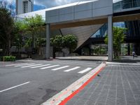 a pedestrian crossing over a red painted line on the road near buildings and trees in the background