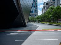 a yellow traffic light on top of a street next to tall buildings, near some grass, and red curb