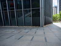 an empty sidewalk in front of a tall building next to trees and grass on the sidewalk