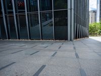 an empty sidewalk in front of a tall building next to trees and grass on the sidewalk