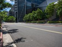 a city street lined with tall buildings and trees, near a sidewalk near bushes and trees