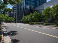 a city street lined with tall buildings and trees, near a sidewalk near bushes and trees