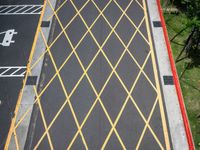 a cross - painted yellow line is on an empty parking lot outside a building in a residential neighborhood