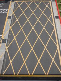 a cross - painted yellow line is on an empty parking lot outside a building in a residential neighborhood