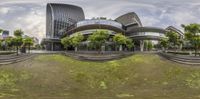 a 360 - 360 view of the city from a grassy area near the sidewalk and the sidewalk, a green lawn, and tall buildings