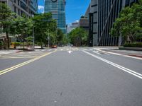 a wide road with buildings and trees in the middle of the road in front of it