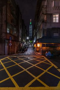 a city street filled with people next to tall buildings at night time, on the side of a road