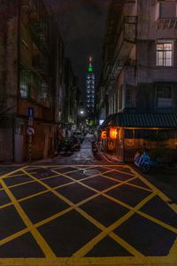 a city street filled with people next to tall buildings at night time, on the side of a road