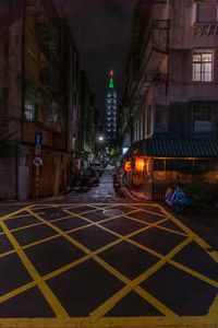 a city street filled with people next to tall buildings at night time, on the side of a road