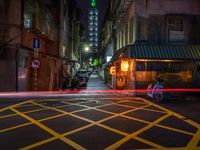 an alley with an umbrella, parked motorcycles and the oriental architecture at night - - a woman sits alone in the dark