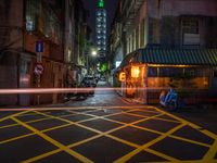 an alley with an umbrella, parked motorcycles and the oriental architecture at night - - a woman sits alone in the dark