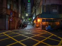 an alley with an umbrella, parked motorcycles and the oriental architecture at night - - a woman sits alone in the dark