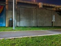 a bicycle parked near a fence, next to a building and street sign at night