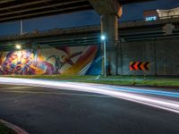 the bright streaks of light shine under a bridge painting in the dark, with the street under the bridge turning on