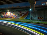 the bright streaks of light shine under a bridge painting in the dark, with the street under the bridge turning on