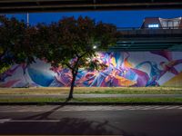 a colorful mural under the highway at night on an overpass in the city of la