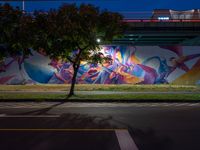 a colorful mural under the highway at night on an overpass in the city of la