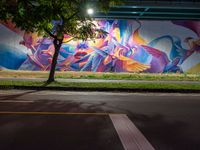 a colorful mural under the highway at night on an overpass in the city of la