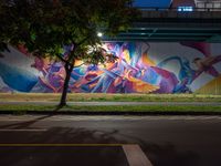 a colorful mural under the highway at night on an overpass in the city of la