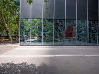 a reflection of a building on the glass wall of a large courtyard, with a red fire hydrant next to the building