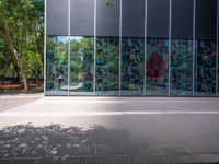 a reflection of a building on the glass wall of a large courtyard, with a red fire hydrant next to the building