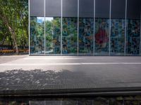 a reflection of a building on the glass wall of a large courtyard, with a red fire hydrant next to the building