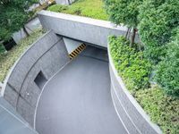 a parking space with concrete walls and green foliages on top of the roof,