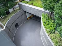 a parking space with concrete walls and green foliages on top of the roof,