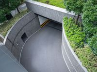 a parking space with concrete walls and green foliages on top of the roof,