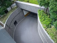 a parking space with concrete walls and green foliages on top of the roof,