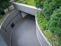 a parking space with concrete walls and green foliages on top of the roof,