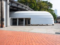 a brick road and red brick pathway in front of a building with a roof that looks like a dome