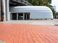 a brick road and red brick pathway in front of a building with a roof that looks like a dome