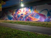 a streetlight shines down on a colorful wall painted by the graffiti artist who has painted his image