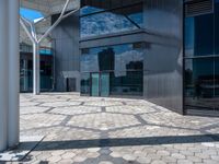 a view of an empty courtyard in front of a building with windows on a sunny day