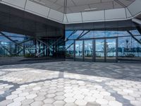 the ground is hexagonal tile with glass doors and windows reflecting a body of water