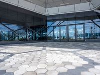 the ground is hexagonal tile with glass doors and windows reflecting a body of water