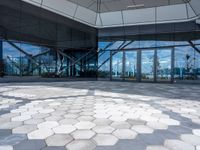 the ground is hexagonal tile with glass doors and windows reflecting a body of water