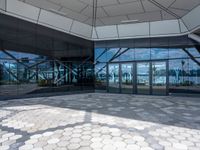 the ground is hexagonal tile with glass doors and windows reflecting a body of water